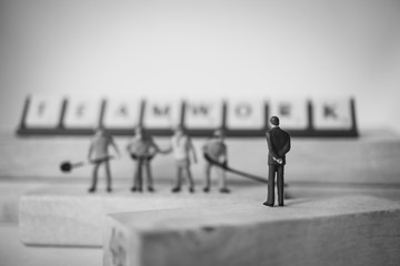 Miniature people, chief and engineer team standing on wooden block using as industry and business concept - Black and white filter