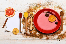 Spices Scattered All Over Wooden Surface. Plate And Spoons With Dried Orange And Chilly Pepper On White Wooden Background. Spices As Grinded Red Pepper And Curcuma Powder Scattered. Culinary Concept