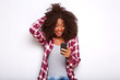 © mimagephotos - young african american woman looking at mobile phone with surprised expression on white background