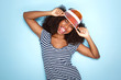 © mimagephotos - trendy young african woman in cap sticking out tongue over blue background