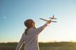 Girl in aviator hat playing pilot with toy plane outside