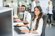 © Bojan - Beautiful and cheerful young woman and man telephone operators with headsets working on desktop computer in customer service call support helpline business center