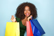 © mimagephotos - cheerful young african woman with shopping bags on blue background
