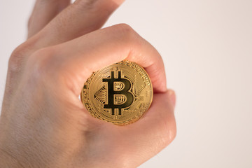 A hand holding Golden Bitcoin - virtual money on blur background.