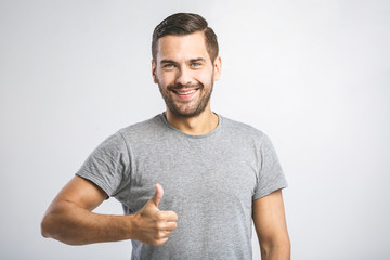 Happy young man. Portrait of handsome young man smiling while standing against white background. Thumbs up.