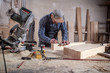 © Виталий Сова - experienced carpenter in work clothes and small buiness owner measures a wooden board with a ruler and marks with pencil the necessary points for slices