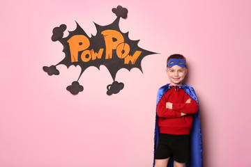 Cute boy in superhero costume on color background