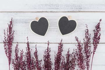 Two heart shape board decorate with violet dried flower on white wood background