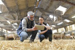 © goodluz - Sheep breeder with veterinary in shed using digital tablet
