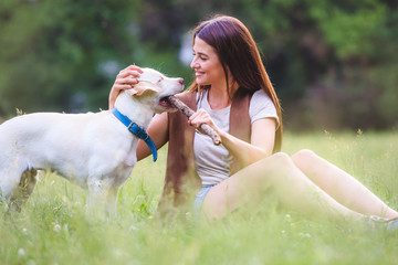 Beautiful young girl playing with a puppy Labrador Retriever in the park 