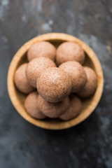 Poster - Nachni laddu or Ragi laddoo or balls made using  finger millet, sugar and ghee. It's a healthy food from India. Served in a bowl or plate over moody background. Selective focus