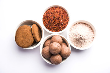 Wall Mural - Nachni / Ragi laddu and biscuits or cookies made using  finger millet, sugar and ghee. It's a healthy food from India. Served in a bowl or plate with raw whole and powder. Selective focus