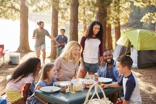 Family With Friends Camp By Lake On Hiking Adventure In Forest