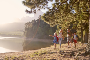 Children Walk By Lake With Parents On Family Hiking Adventure