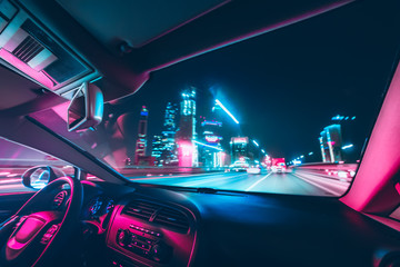 Car speed drive on the road in night city. Retro wave neon noir lights color toning