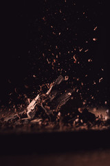 Wall Mural -  closeup view of grated dark chocolate falling on pieces of chocolate on black background