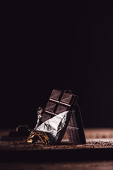 Wall Mural - closeup shot of two arranged chocolate bars on wooden table on black background