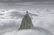 A man standing on a stone cliff over the clouds