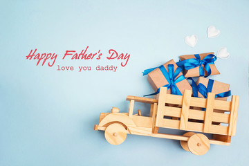 Wall Mural - Father's Day greeting message with wooden toy truck with gift box in the back on blue background.