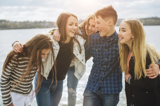 summer holidays and teenage concept - group of smiling teenagers with skateboard hanging out outside