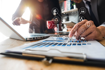 Working team meeting concept,businessman using smart phone and laptop and digital tablet computer in modern office with virtual interface icons network diagram at modern office in morning light