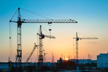 Canvas Print - Industrial landscape with silhouettes of constraction cranes on sunset background