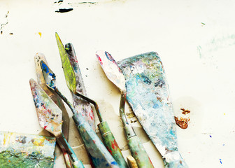 Various palette knives in oil paint after use on the table. Artist Tools