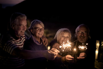 four senior adult people celebrate with sparkle fire light at the night for new year eve or just for