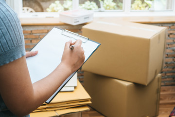 Happy woman checking stuff in cardboard box before sent to transportation company and movin