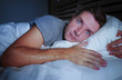 © TheVisualsYouNeed - restless worried young attractive man awake at night lying on bed sleepless with eyes wide opened suffering insomnia sleeping disorder depressed