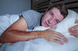 © TheVisualsYouNeed - restless worried young attractive man awake at night lying on bed sleepless with eyes wide opened suffering insomnia sleeping disorder depressed