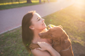 Canvas Print - Happy, pretty girl hugging her dog while outdoors. Hug with a dog in close-up. Smiling girl and pet at a walk in the park.