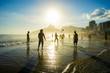 Silhouettes of Brazilians playing keepy uppy altinho beach soccer on the sunset shore on Ipanema Beach