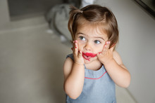 Little Girl With Smeared Lipstick On Face And Surprised Expression