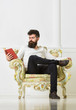 © be free - Lecturer smart sit on armchair and reads book, white wall background. Scientist, professor on pensive face enjoys literature. Man with beard and mustache spends leisure with book. Intelligent concept.