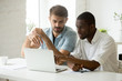 © fizkes - Multiethnic work group of two working at laptop pc, discussing developing company strategy, negotiating, brainstorming. Colleague pointing at screen explaining matters to coworker. Diversity concept
