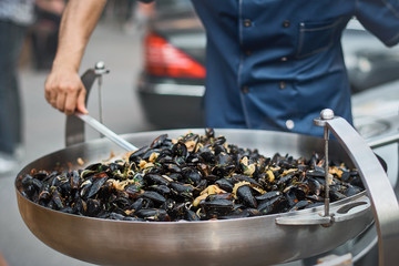 Wall Mural - Preparation of mussels. Mussels in a frying pan. Street food.