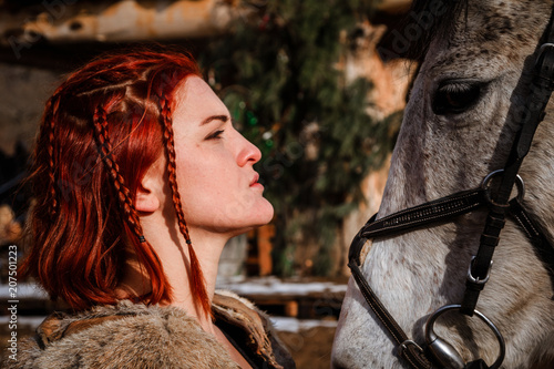 Fotografie, Obraz Red-haired woman with a faithful horse preparing for battle