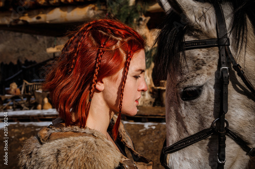 Fotografie, Obraz Red-haired woman with a faithful horse preparing for battle