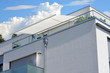 Moderne verglaste Balkone mit elektrischer Markise, Edelstahl-Geländer, Regenfallrohr und Dachrinne an Neubau-Hausfront