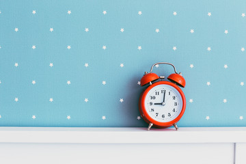 red alarm clock, white bed, blue wall, nine hours, morning