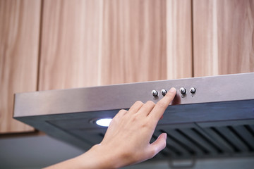 caucasian women hand using the range hood in modern kitchen