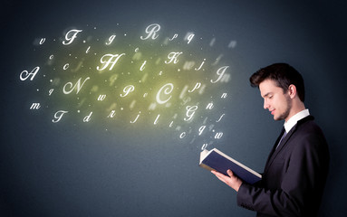 Wall Mural - Casual young man holding book with shiny letters flying out of it
