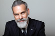 © SFIO CRACHO - Portrait of attractive middle aged bearded gentleman wearing trendy suit over empty gray background. Studio shot, business fashion concept.