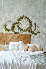 Wall Mural - Hanging wooden bed suspended from ceiling with pillows and cozy white plaid and knitted blanket, copy space. Rings with eucalyptus sprigs. Trendy room design. Loft interior in scandinavian style