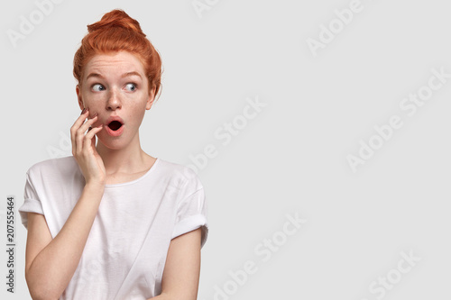 Portrait Of Surprised Freckled Young Female With Ginger Hair Bun