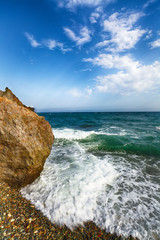 Wall Mural - Sea waves crashing on the shore and flowing above seashore pebbles