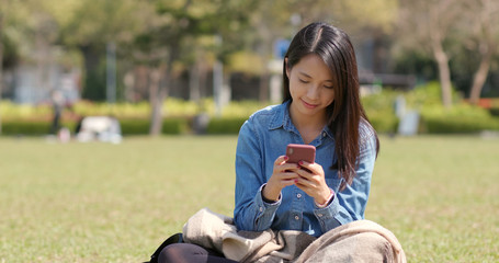 Canvas Print - Young woman use of mobile phone and sitting on green lawn