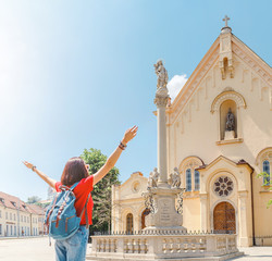 Wall Mural - Active and happy girl tourist traveler enjoys a marvelous view of the architecture of the old Capuchin church in Brastilava, Slovakia