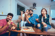 © Mediteraneo - Group of young friends eating pizza and watching tv.Home party.Fast food concept.